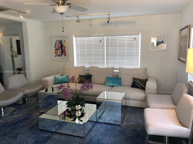 a living room with furniture a large window and a chandelier