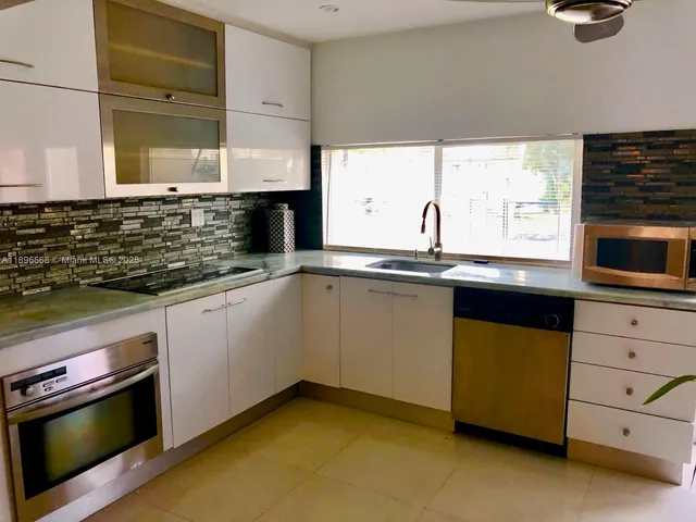 a kitchen with granite countertop a sink a stove and cabinets