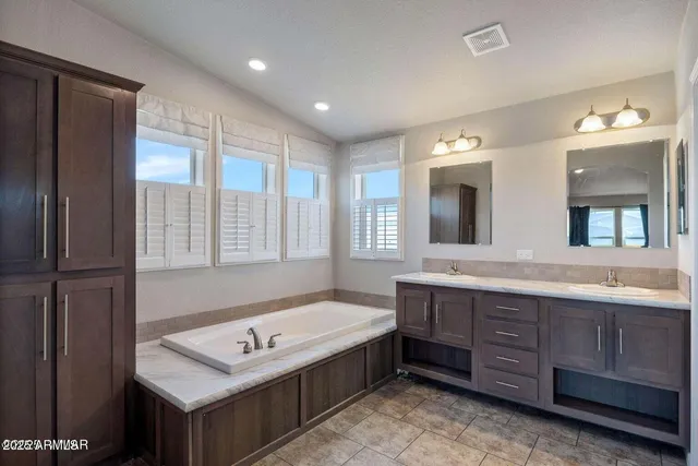 a bathroom with a tub a double vanity sink and a large mirror