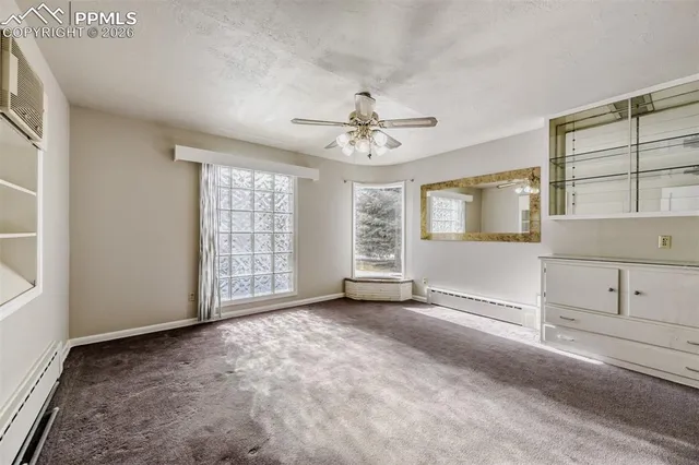 an empty room with chandelier fan and windows