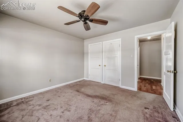 an empty room with a ceiling fan and carpet