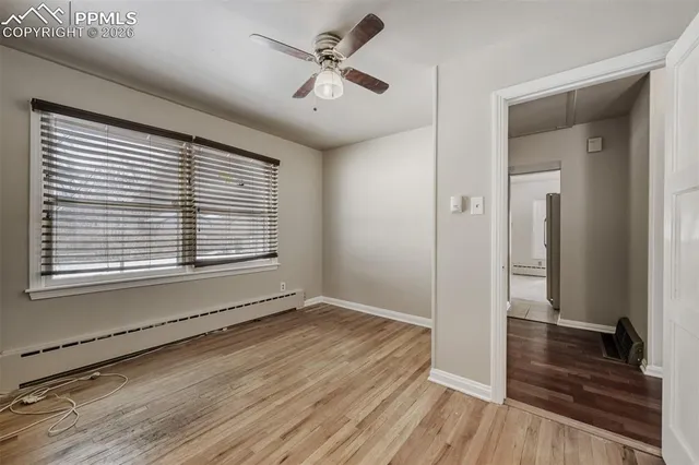 a view of empty room with wooden floor and fan