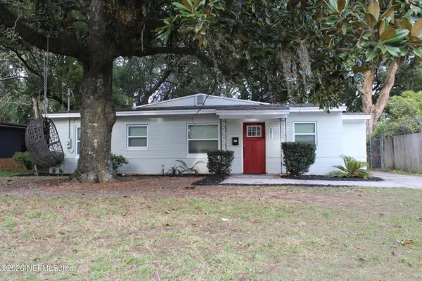 a view of a house with a yard and large tree