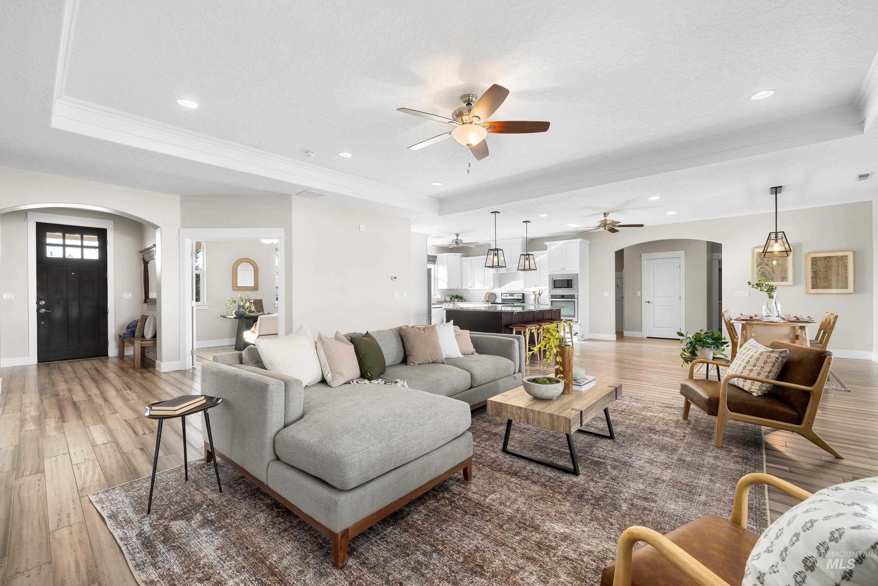 8018 Plumberry Court Middleton, ID 83644 - Photo 11 of 50 Living room with arched walkways, light wood finished floors, a tray ceiling, recessed lighting, and crown molding