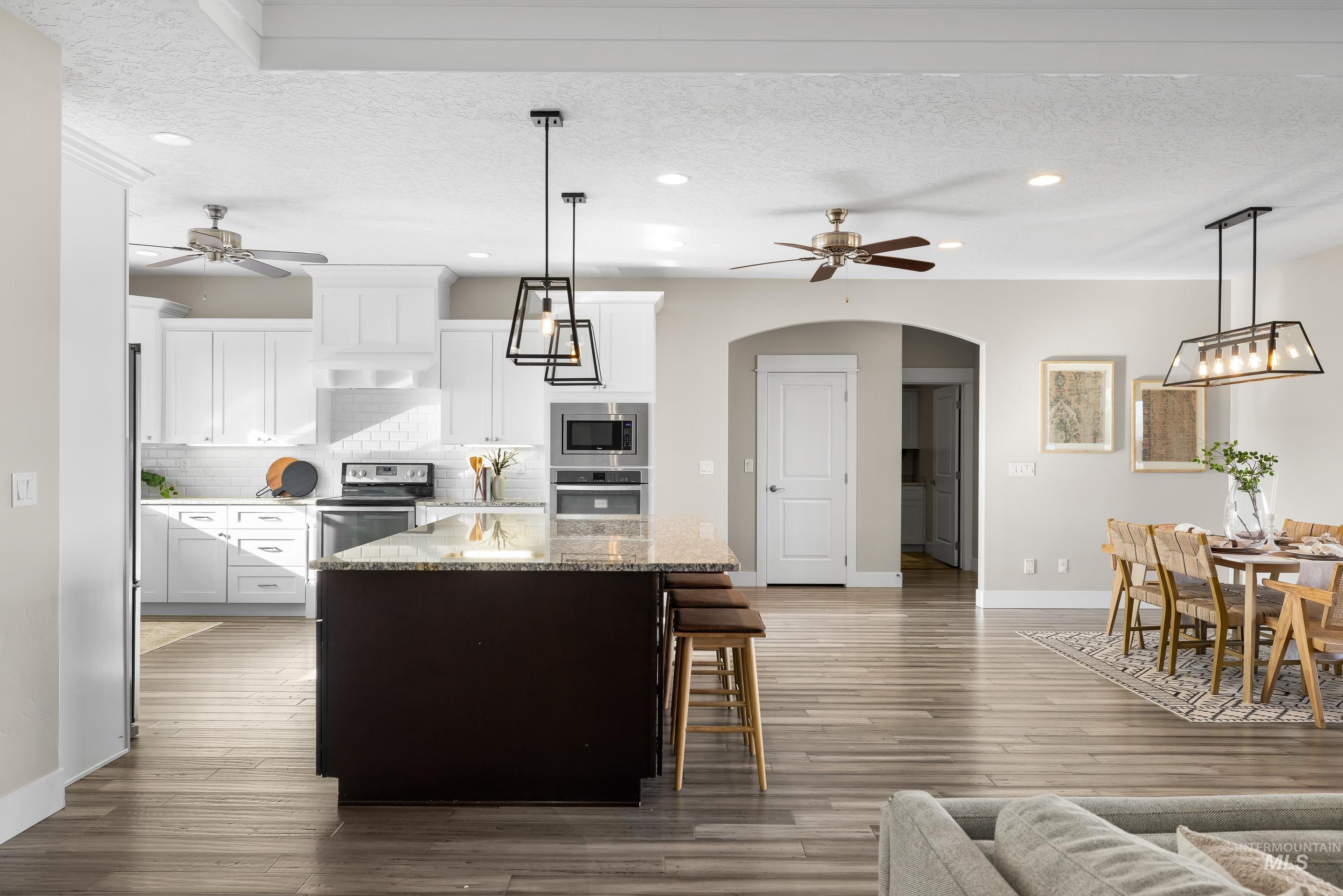 8018 Plumberry Court Middleton, ID 83644 - Photo 16 of 50 Kitchen with ceiling fan, pendant lighting, white cabinets, a textured ceiling, and a kitchen island