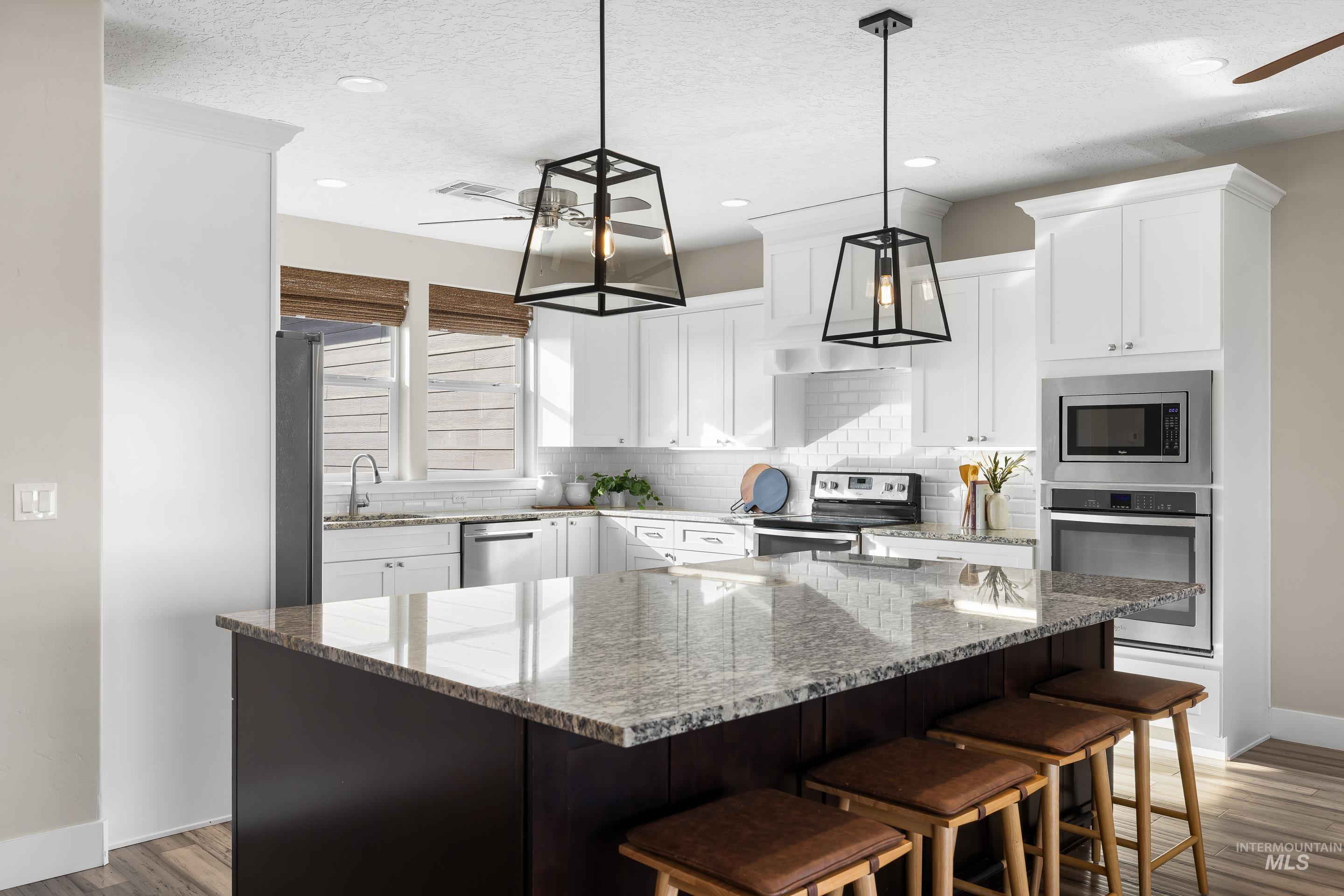 8018 Plumberry Court Middleton, ID 83644 - Photo 17 of 50 Kitchen featuring a ceiling fan, stainless steel appliances, light stone counters, a textured ceiling, and recessed lighting
