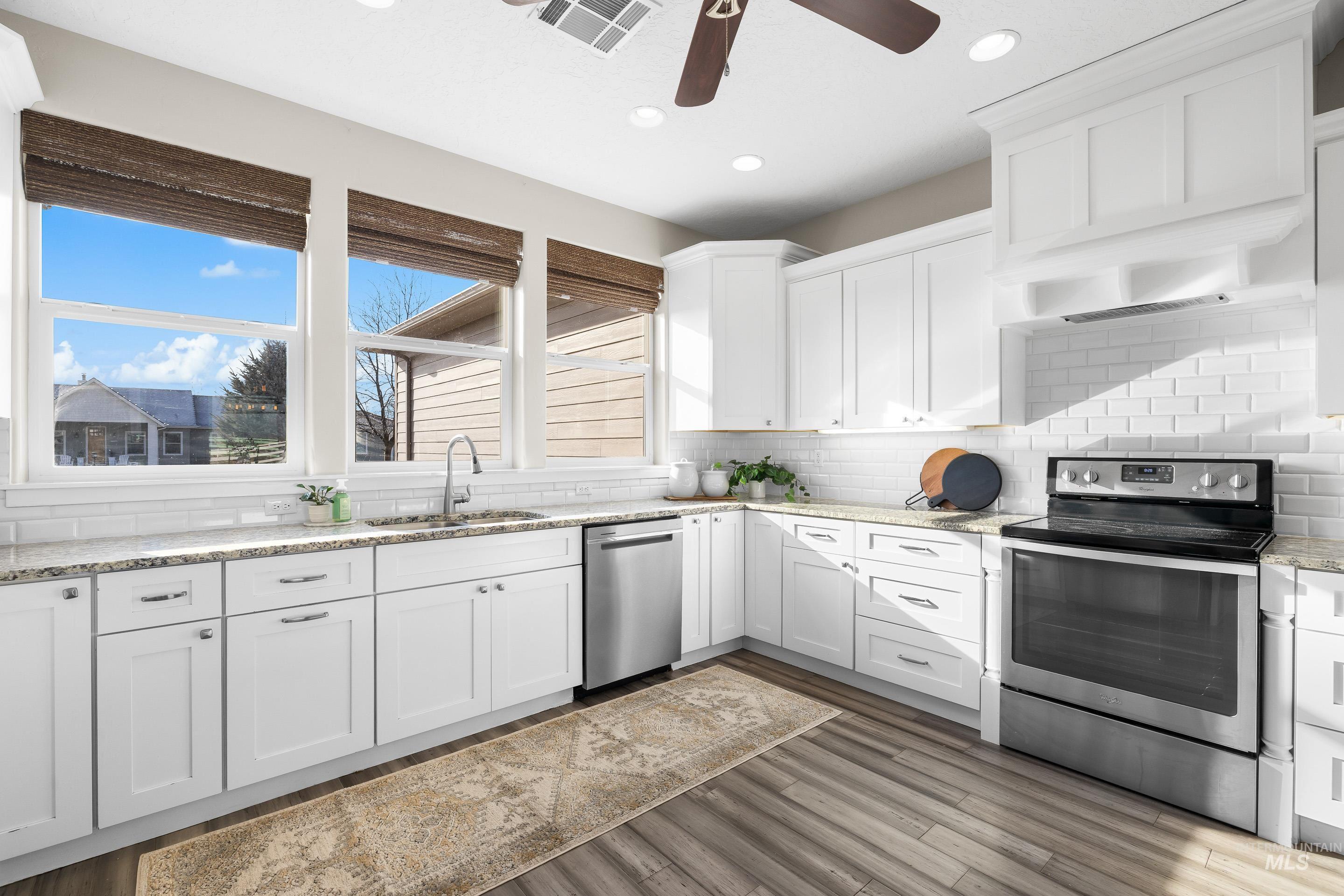8018 Plumberry Court Middleton, ID 83644 - Photo 19 of 50 Kitchen with appliances with stainless steel finishes, white cabinets, light stone countertops, under cabinet range hood, and recessed lighting
