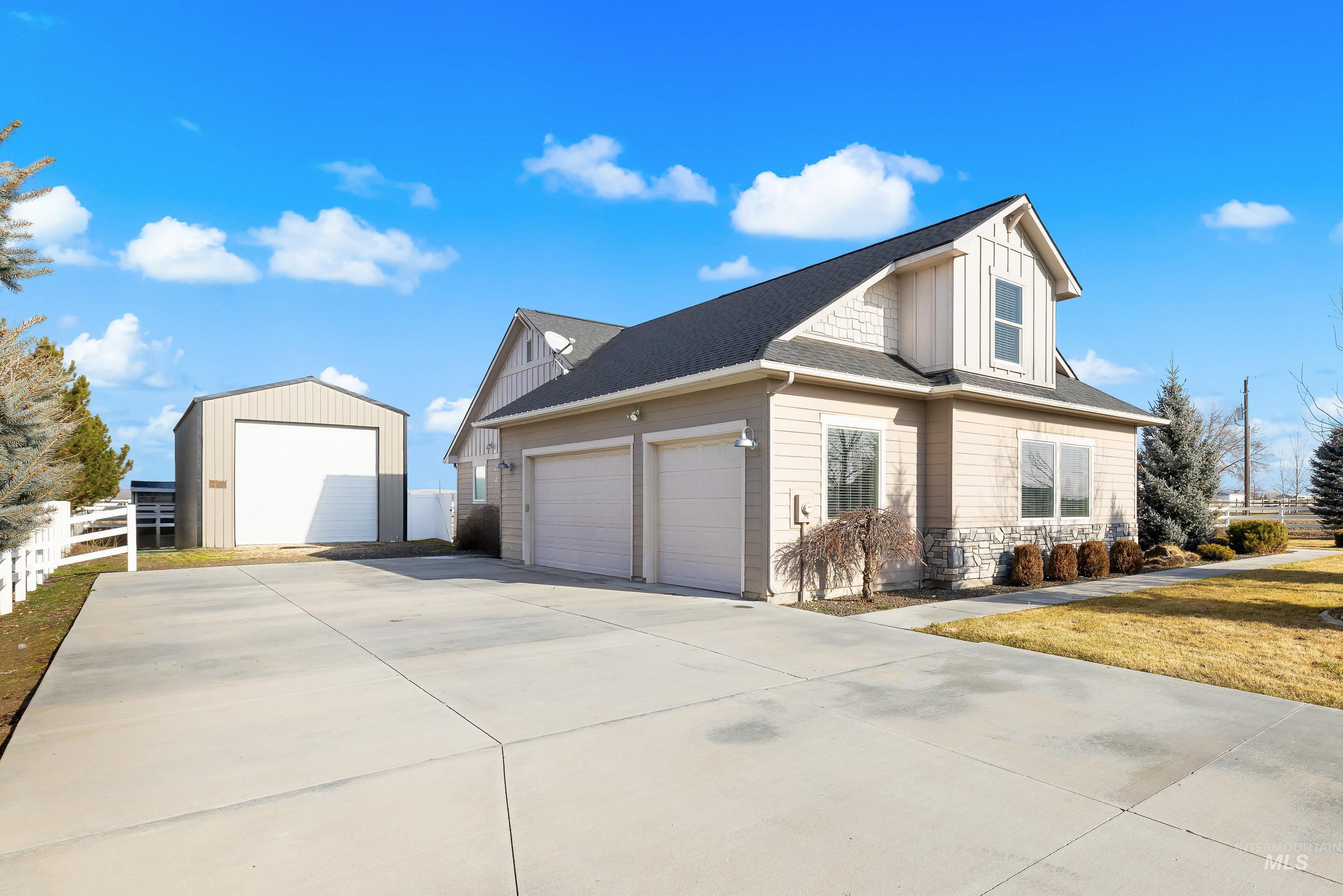 8018 Plumberry Court Middleton, ID 83644 - Photo 4 of 50 View of home's exterior featuring stone siding, a shingled roof, board and batten siding, concrete driveway, and an outbuilding