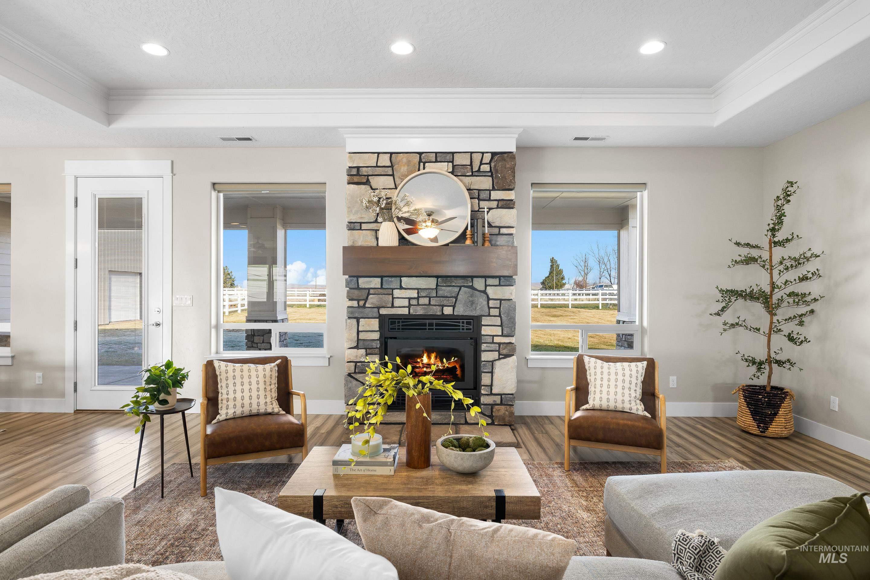 8018 Plumberry Court Middleton, ID 83644 - Photo 6 of 50 Living area featuring healthy amount of natural light, crown molding, a stone fireplace, wood finished floors, and a textured ceiling