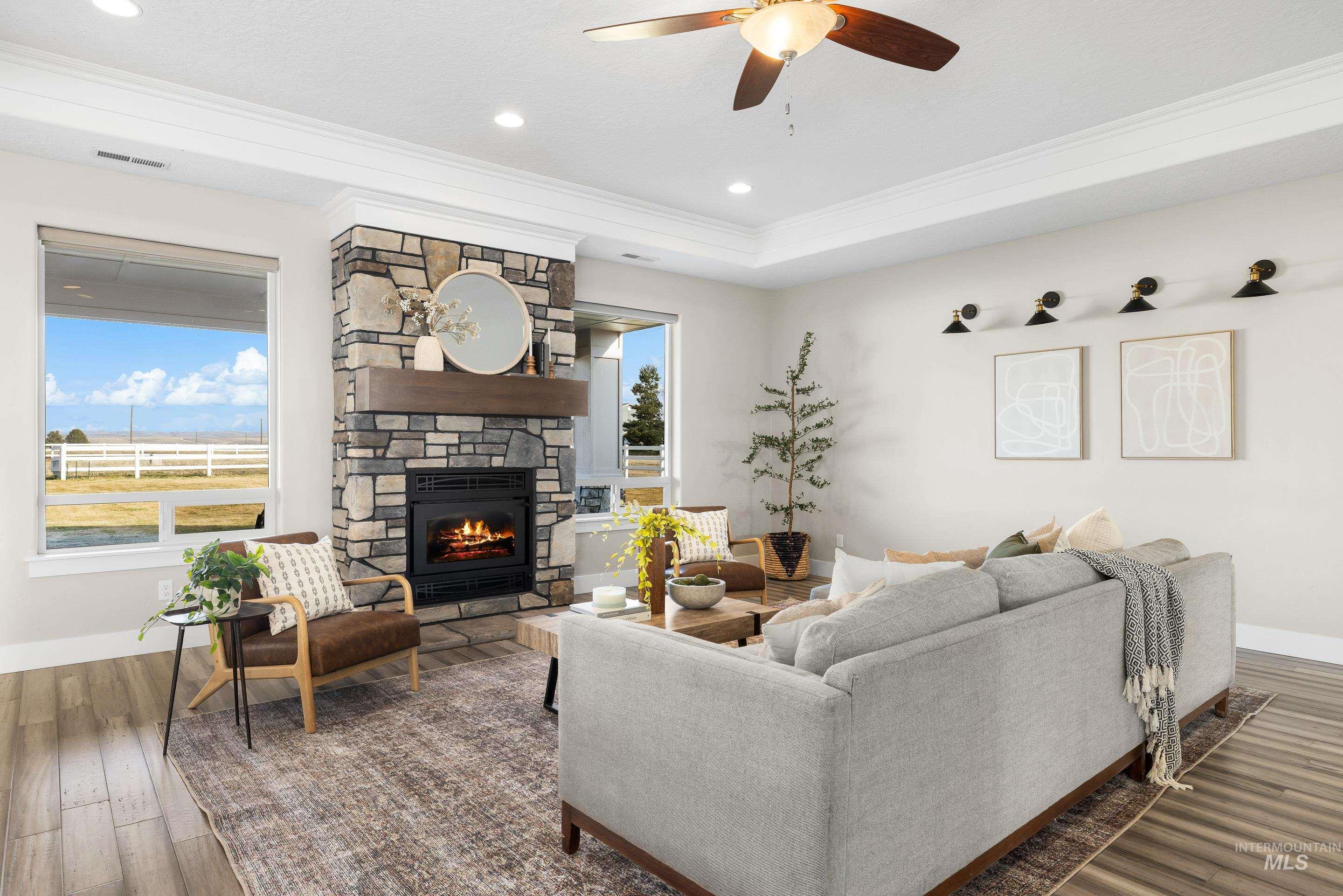8018 Plumberry Court Middleton, ID 83644 - Photo 7 of 50 Living area with dark wood-style floors, a stone fireplace, healthy amount of natural light, crown molding, and ceiling fan