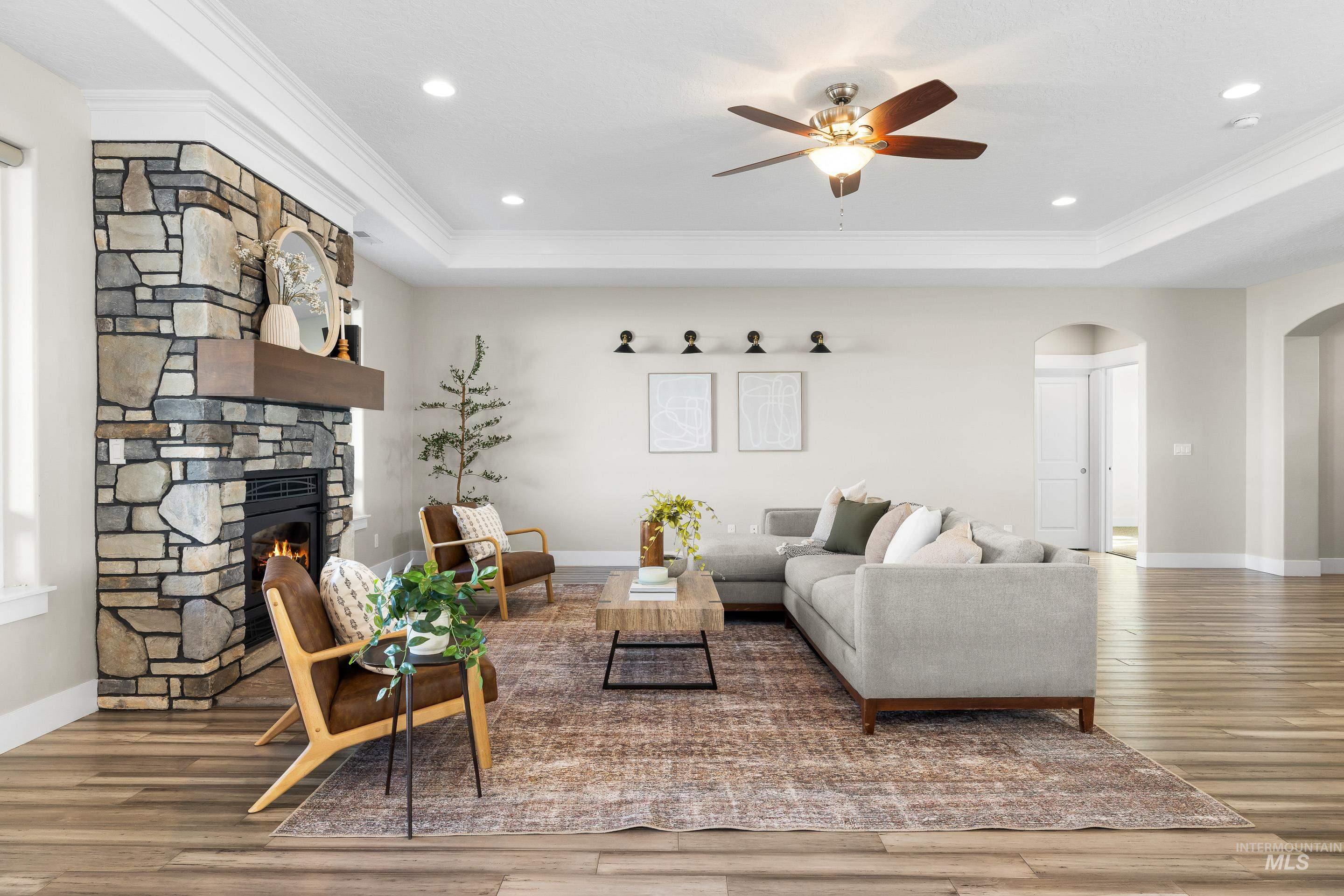 8018 Plumberry Court Middleton, ID 83644 - Photo 8 of 50 Living area with arched walkways, a fireplace, a ceiling fan, wood finished floors, and a raised ceiling