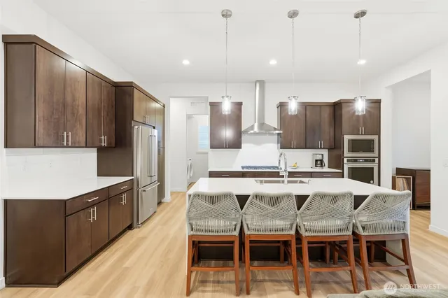 a kitchen with stainless steel appliances kitchen island granite countertop a stove a refrigerator and island with wooden floor