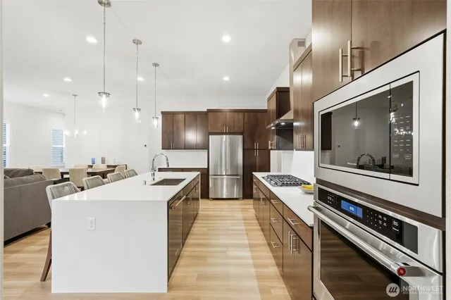 a large kitchen with stainless steel appliances kitchen island a large stove a sink dishwasher and a refrigerator with wooden floor