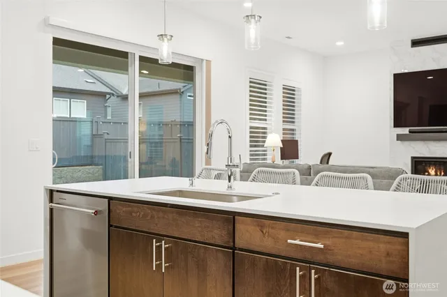 a room with stainless steel appliances kitchen island granite countertop a sink and a refrigerator