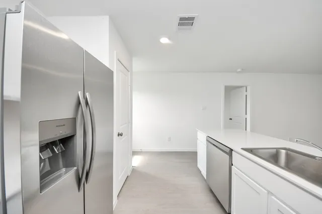a kitchen with a sink a stove a refrigerator and white cabinets