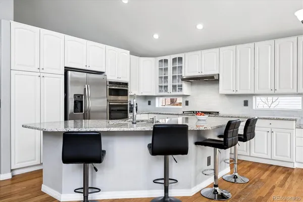 a kitchen with stainless steel appliances kitchen island granite countertop a stove a refrigerator and a chair