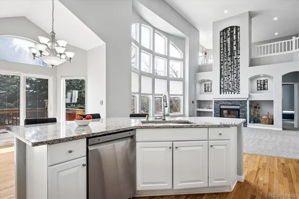 a open kitchen with granite countertop a sink and dishwasher with white cabinets