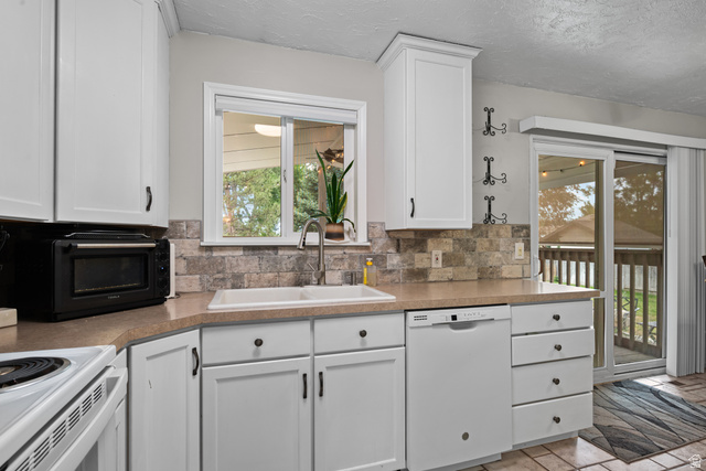 7659 State Street Midvale, UT 84047 - Photo 9 of 33 White shaker-style cabinetry with black hardware, complementing a light-toned countertop and a multi-toned tile backsplash