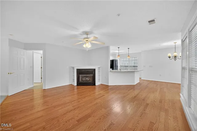 a view of empty room with wooden floor and kitchen view