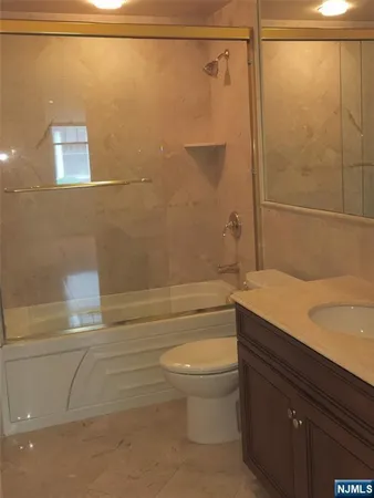 a bathroom with a granite countertop bathtub shower sink vanity and toilet