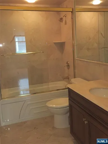 a bathroom with a granite countertop bathtub shower sink vanity and toilet