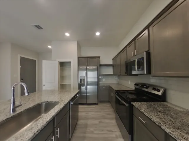 a kitchen with stainless steel appliances granite countertop a sink stove and refrigerator