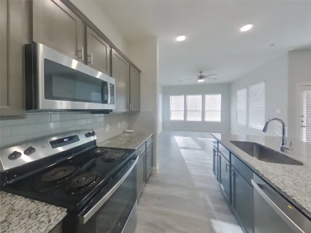 a kitchen with stainless steel appliances granite countertop a sink stove and microwave