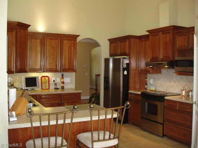 8204 Damson Court Oak Ridge, NC 27310 - Photo 4 of 7 Other. Kitchen features cherry cabinetry, solid surface countertops, porcelain tile floor and backsplash, vaulted ceiling, upgraded stainless appliances