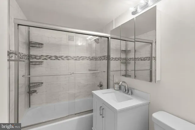 a bathroom with a shower sink vanity mirror and toilet