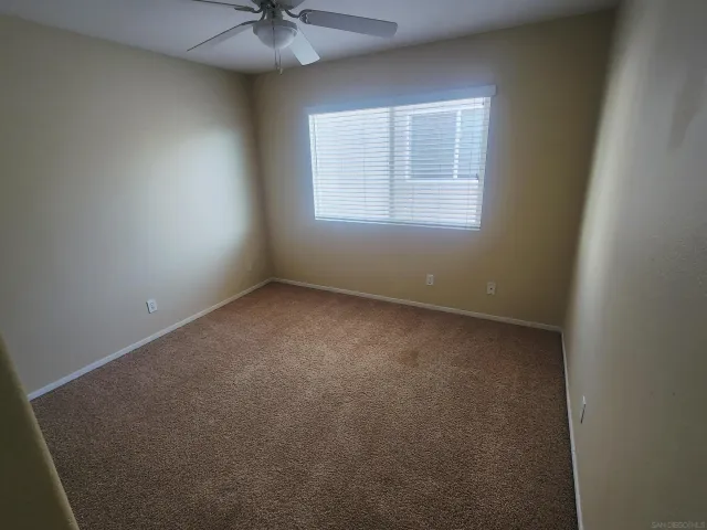 an empty room with a chandelier fan and windows