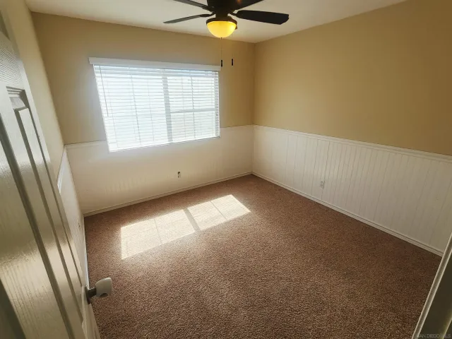 an empty room with windows and fan