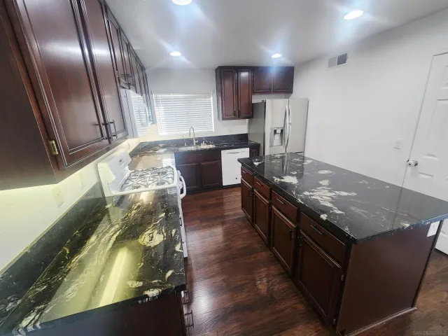 a large kitchen with stainless steel appliances granite countertop a stove a sink and a refrigerator