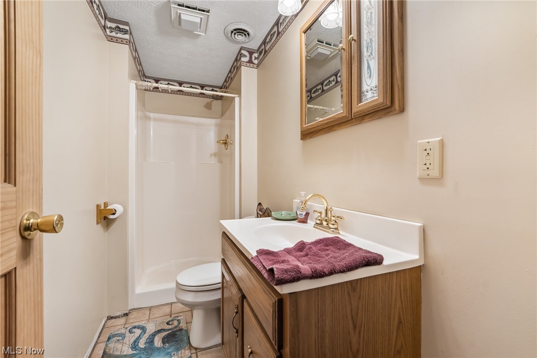 620 Ridgeleigh Street Minerva, OH 44657 - Photo 21 of 35 Bathroom with toilet, a textured ceiling, oversized vanity, tile flooring, and a shower