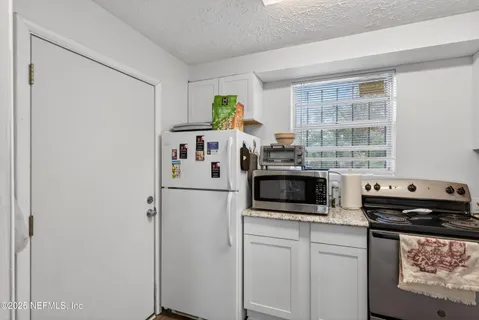 a kitchen with stainless steel appliances granite countertop white cabinets and a stove a sink