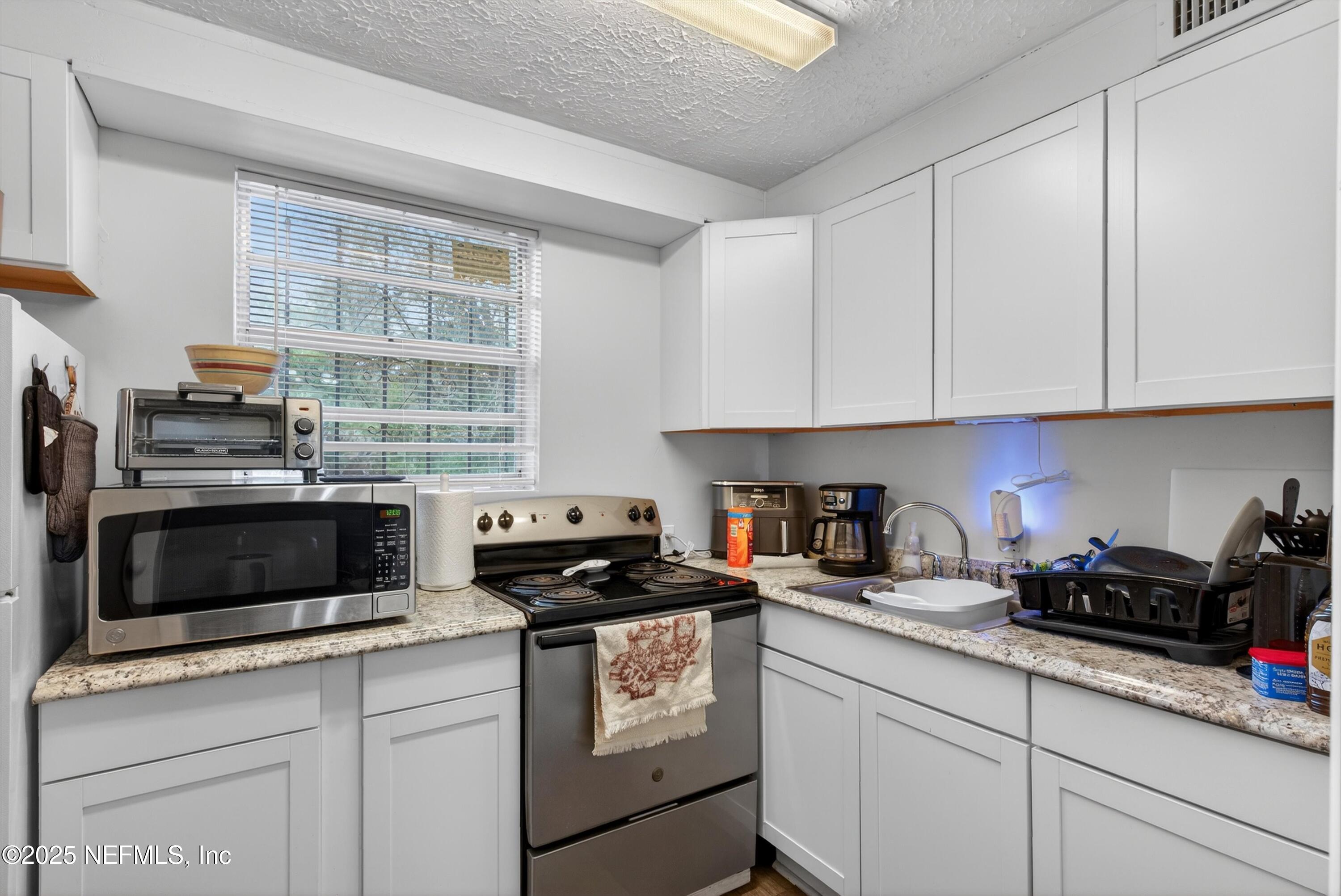2570 Spirea Street Jacksonville, FL 32209 - Photo 9 of 19 a kitchen with stainless steel appliances granite countertop white cabinets and a stove a sink