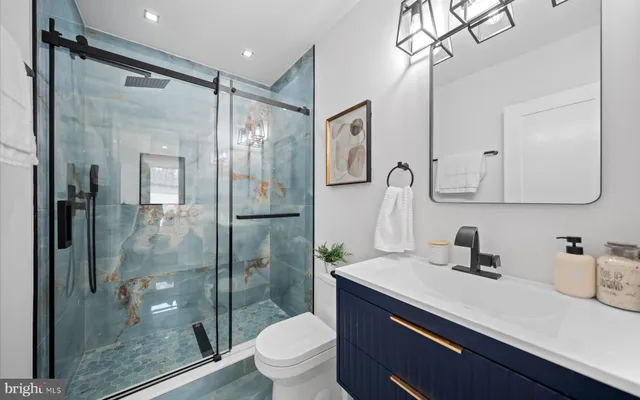 a bathroom with a shower sink vanity mirror and toilet