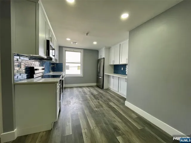 a kitchen with green cabinets and wooden floor