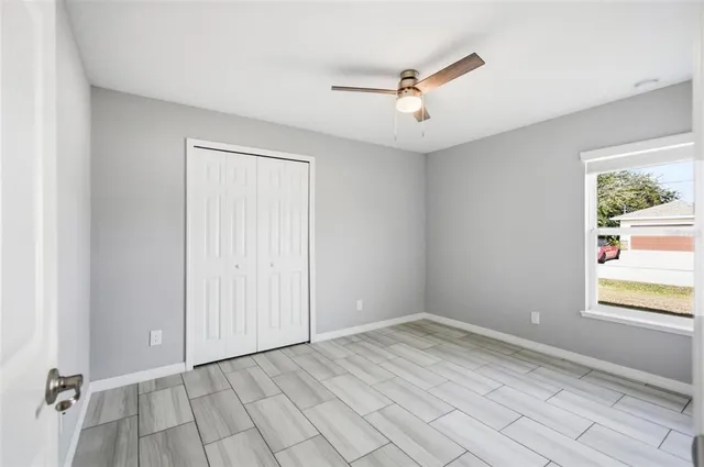 a view of an empty room with window and chandelier fan