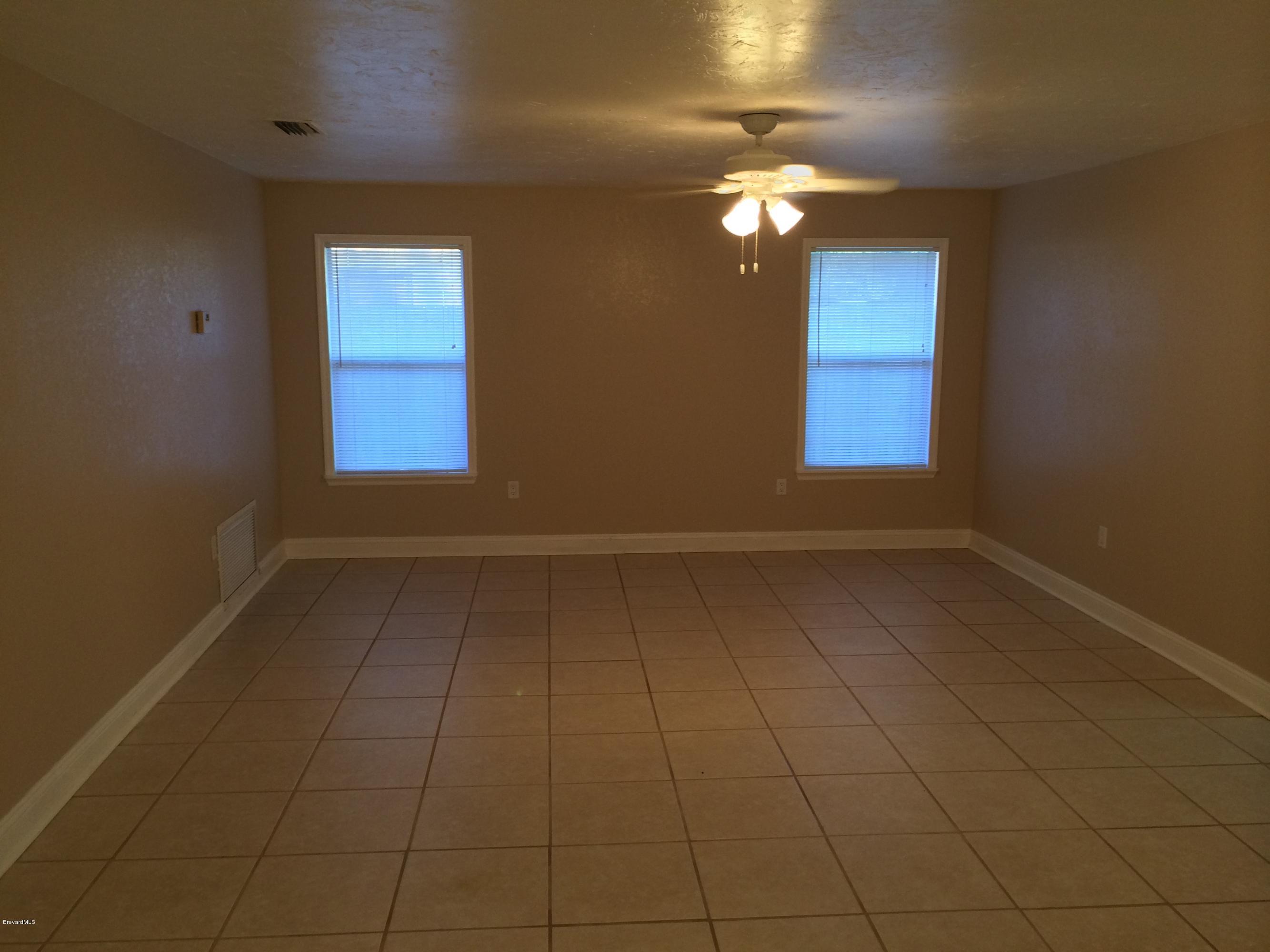 6151 Corning Road Cocoa, FL 32927 - Photo 11 of 13 en empty room with windows and chandelier fan