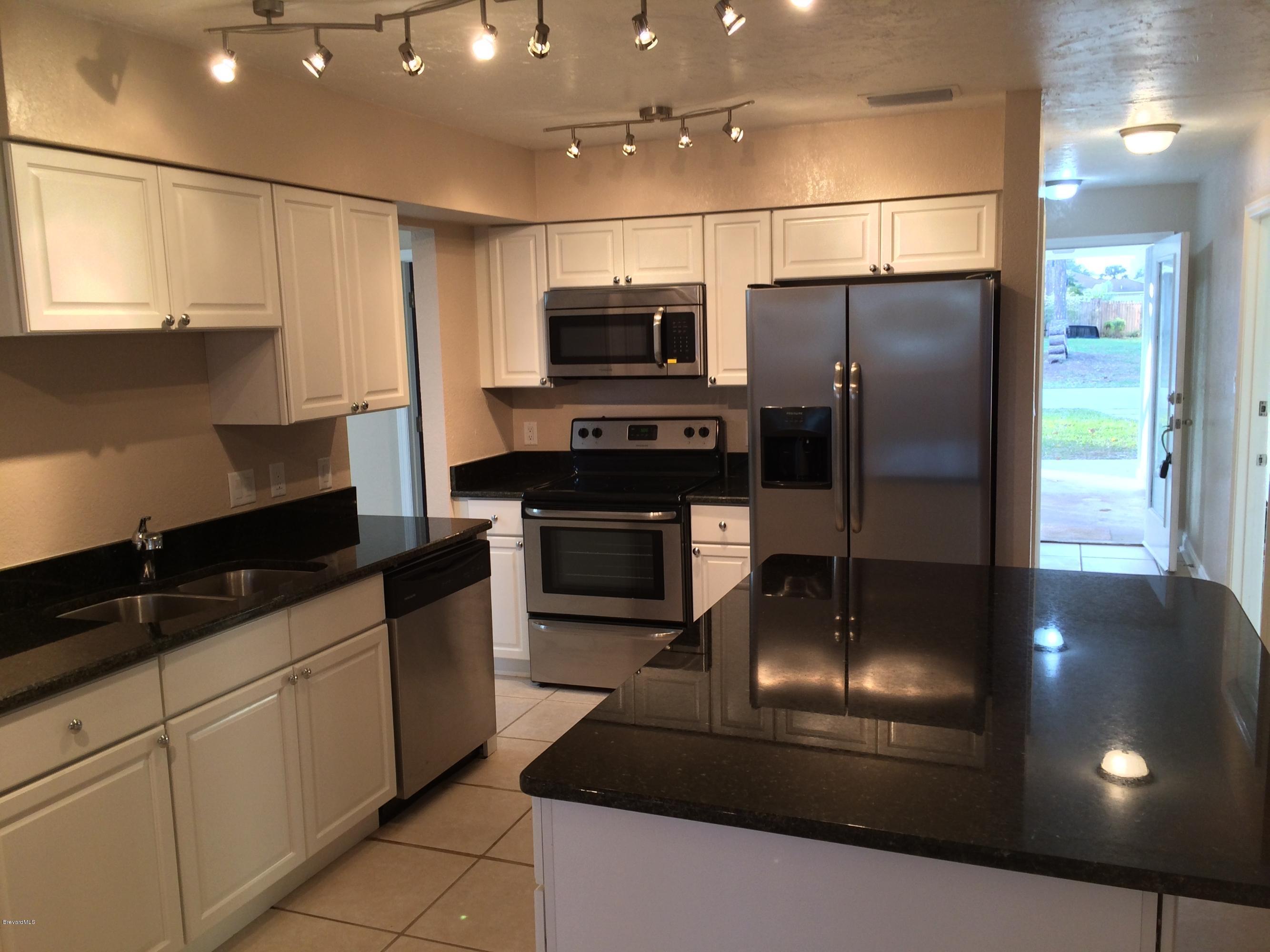 6151 Corning Road Cocoa, FL 32927 - Photo 8 of 13 a kitchen with stainless steel appliances granite countertop a refrigerator a sink a stove and oven