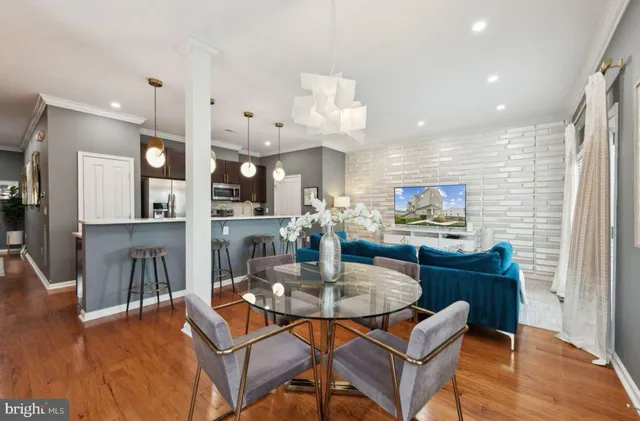 a dining room with wooden floor and kitchen view