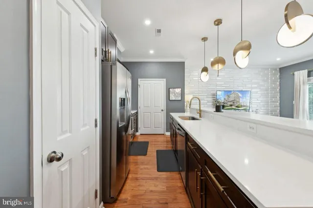 a large kitchen with a large counter top space a sink a refrigerator and cabinets