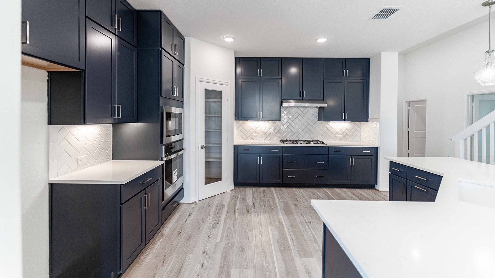 294 Rubber Tree Way Buda, TX 78610 - Photo 5 of 19 Kitchen featuring light stone counters, light wood-style floors, decorative light fixtures, stainless steel appliances, and decorative backsplash