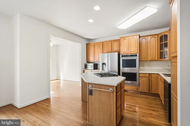 a kitchen with stainless steel appliances granite countertop a refrigerator a stove and a sink with wooden floor