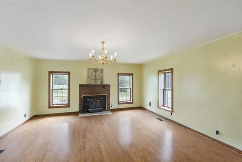 an empty room with chandelier fan and windows