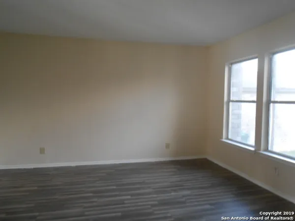 a view of an empty room with window and chandelier fan