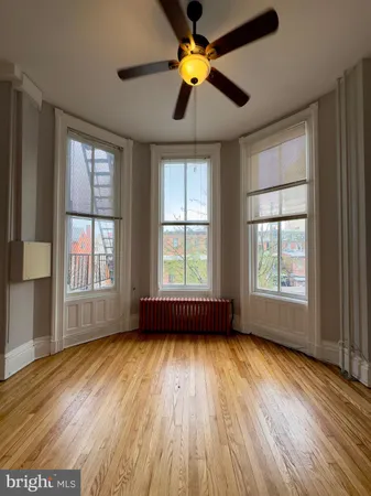 a view of empty room with wooden floor and fan