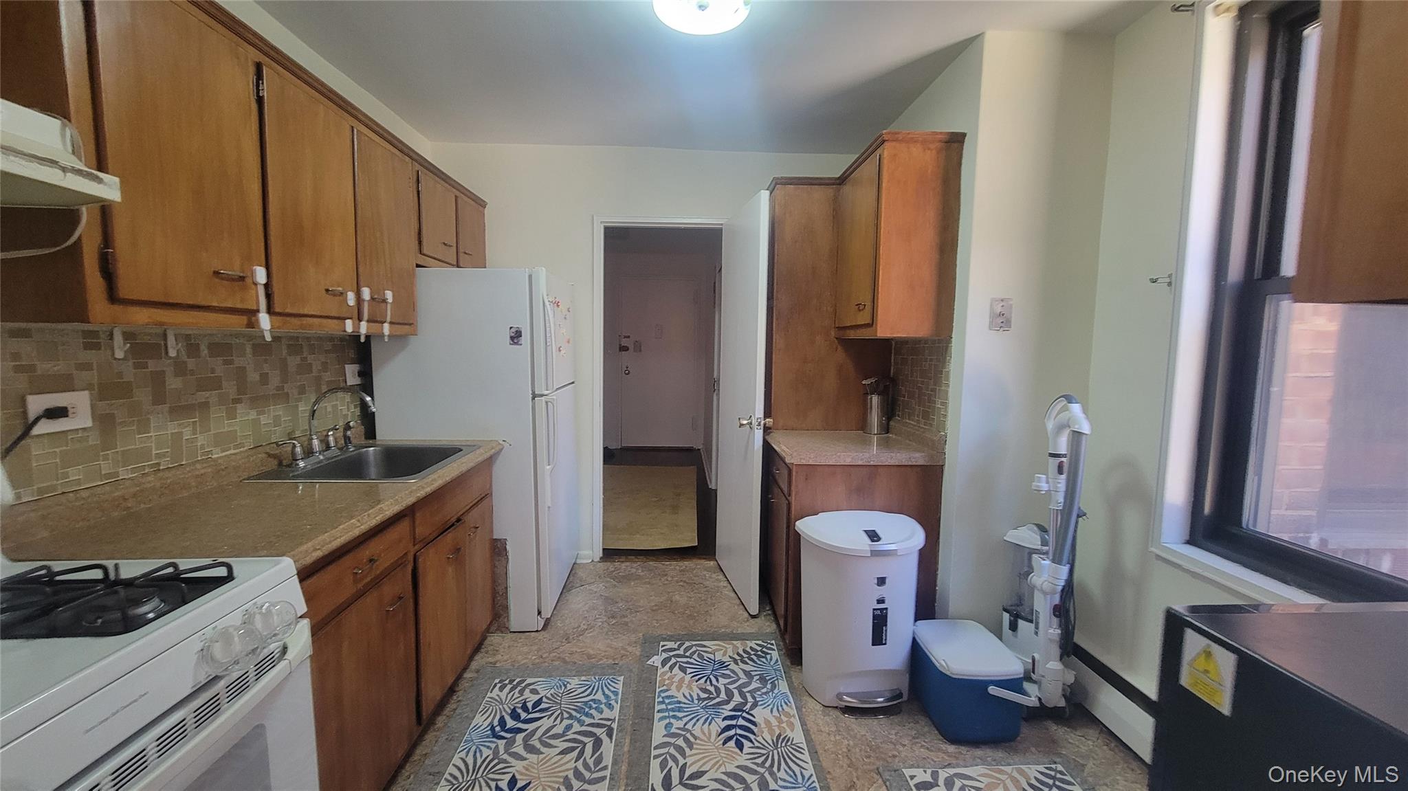 99-06 58th Avenue, Unit 2F Queens, NY 11368 - Photo 13 of 24 a kitchen with a stove sink and refrigerator