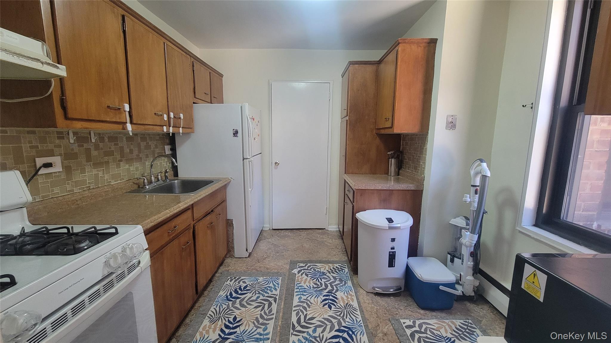 99-06 58th Avenue, Unit 2F Queens, NY 11368 - Photo 14 of 24 a kitchen with a stove and a refrigerator