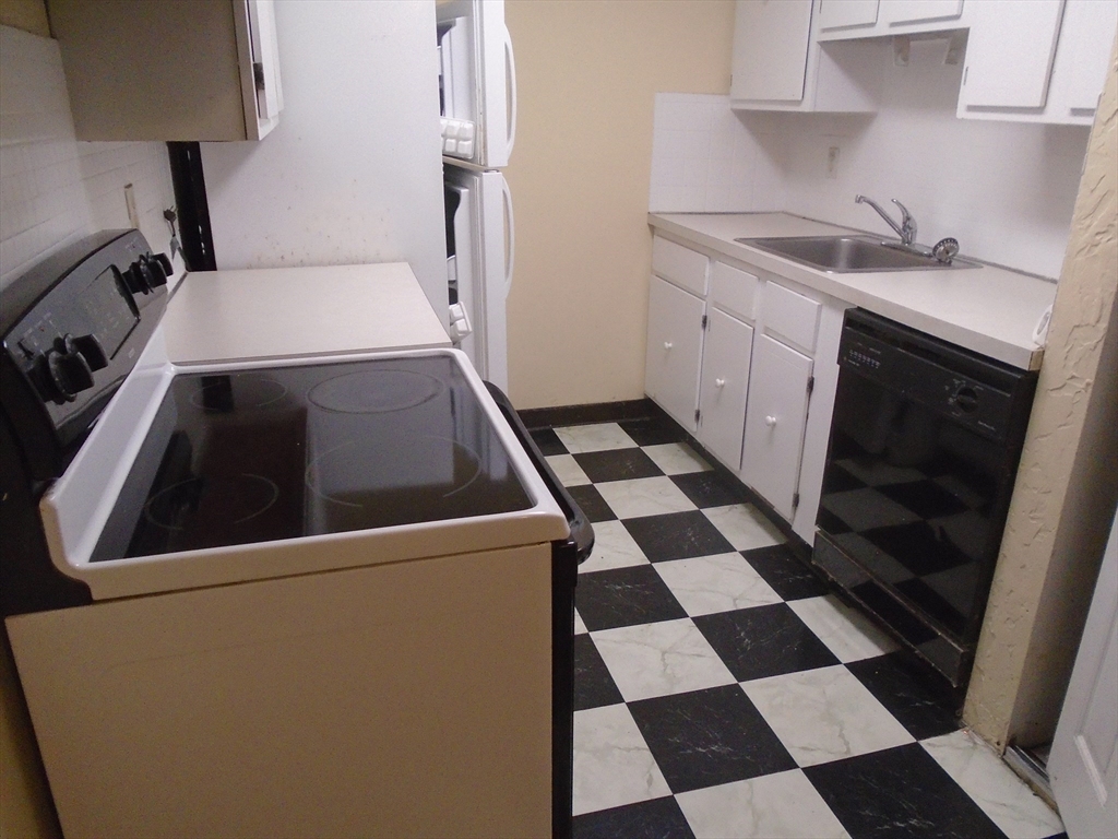 451 School Street, Unit 34 Marshfield, MA 02050 - Photo 7 of 18 a kitchen with a checkered floor and white cabinets